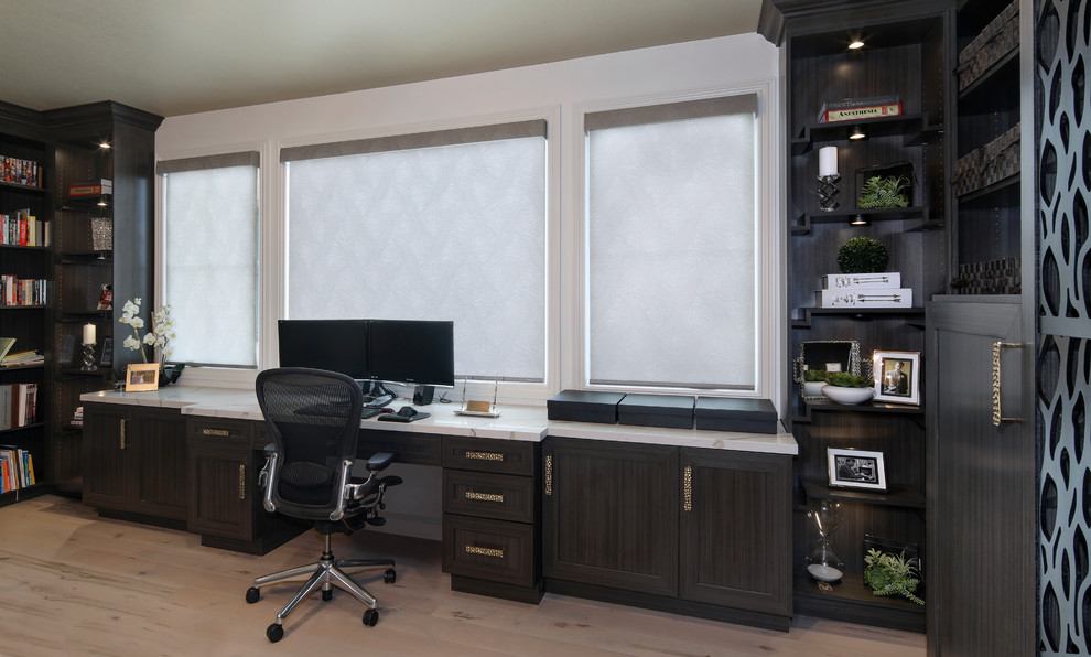 Diseño de despacho contemporáneo de tamaño medio con biblioteca, paredes grises, suelo de madera clara, escritorio empotrado y suelo gris