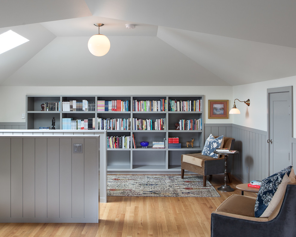 Immagine di un grande studio country con libreria, pareti grigie e parquet chiaro