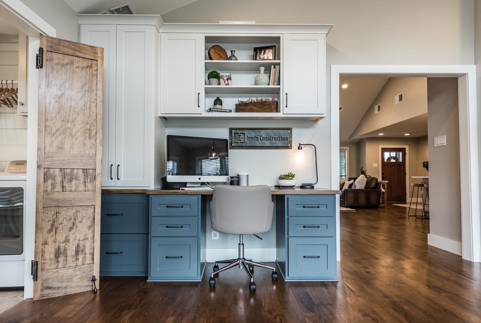 Ejemplo de despacho de estilo de casa de campo de tamaño medio con paredes grises, suelo de madera en tonos medios, escritorio empotrado y suelo marrón