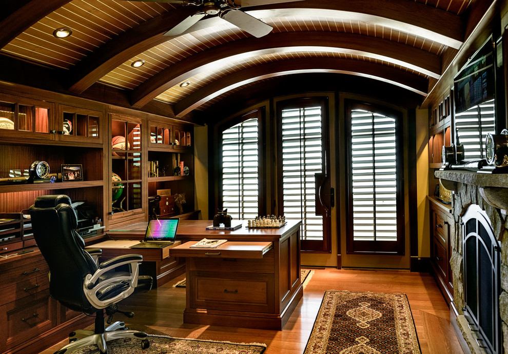 Esempio di un ufficio stile marinaro di medie dimensioni con pareti gialle, pavimento in legno massello medio, camino classico, cornice del camino in pietra e scrivania incassata