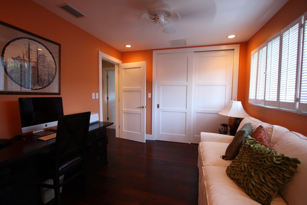 Mittelgroßes Asiatisches Arbeitszimmer mit Arbeitsplatz, oranger Wandfarbe, dunklem Holzboden, freistehendem Schreibtisch und braunem Boden in Tampa