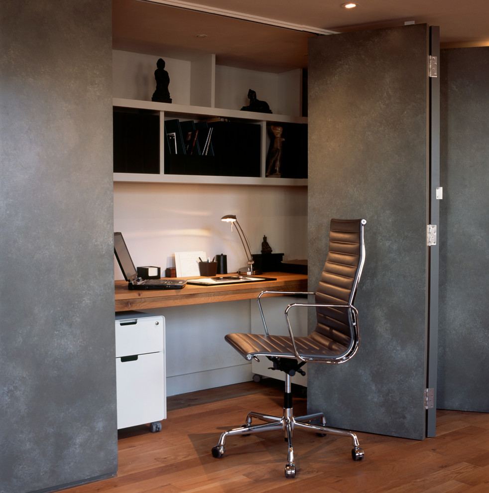 Ejemplo de despacho actual pequeño con paredes grises y suelo de madera en tonos medios