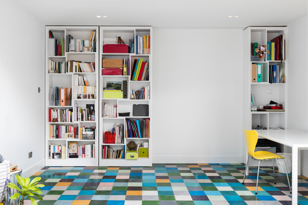 Modern inredning av ett mellanstort hemmabibliotek, med vita väggar, klinkergolv i keramik, ett fristående skrivbord och flerfärgat golv