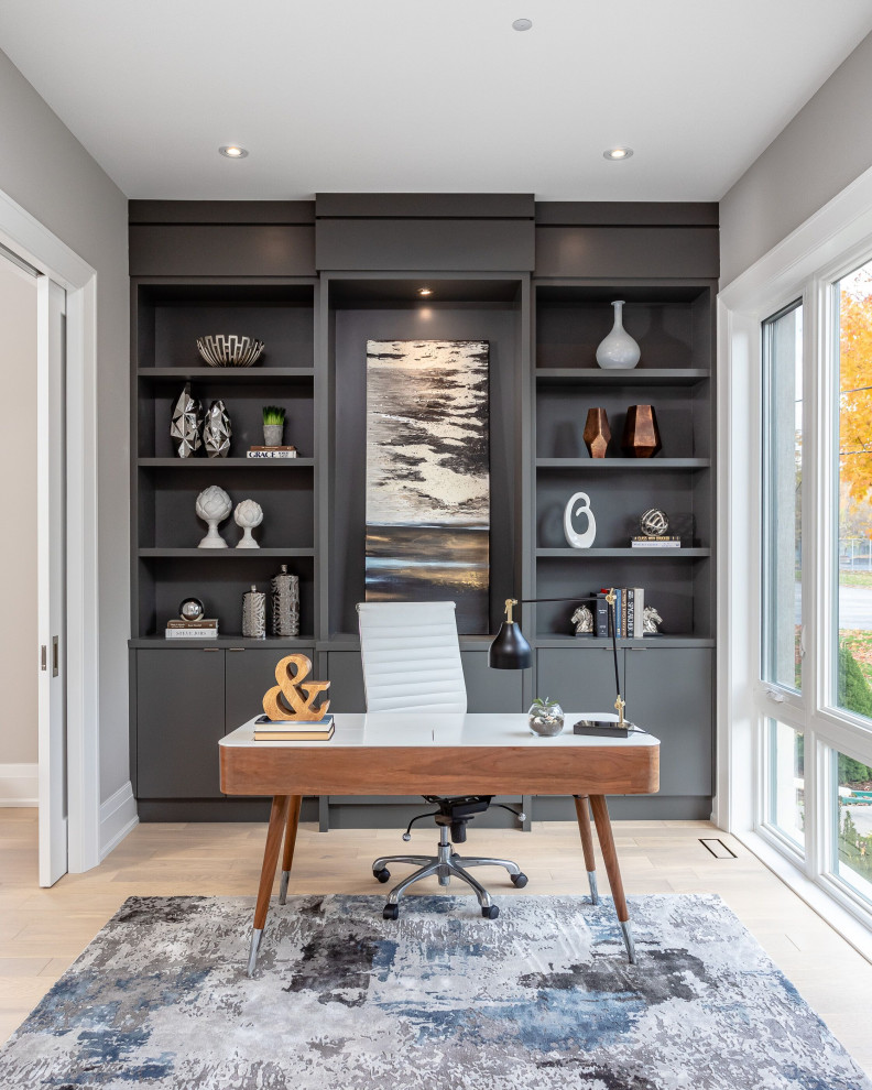 Medium sized contemporary study in Toronto with grey walls, medium hardwood flooring, no fireplace, a freestanding desk and beige floors.