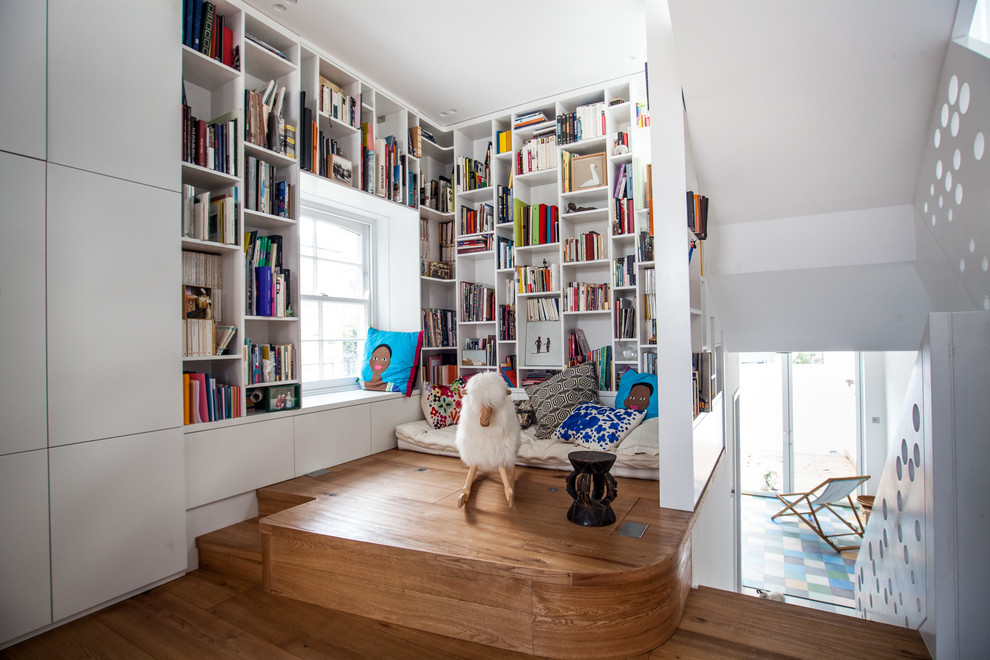 Small trendy medium tone wood floor home office library photo in London with white walls and no fireplace