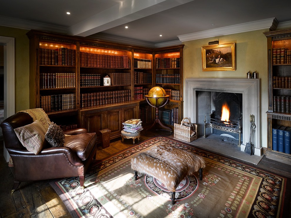 Inspiration för mellanstora klassiska arbetsrum, med ett bibliotek, gula väggar, mörkt trägolv, en standard öppen spis och en spiselkrans i sten