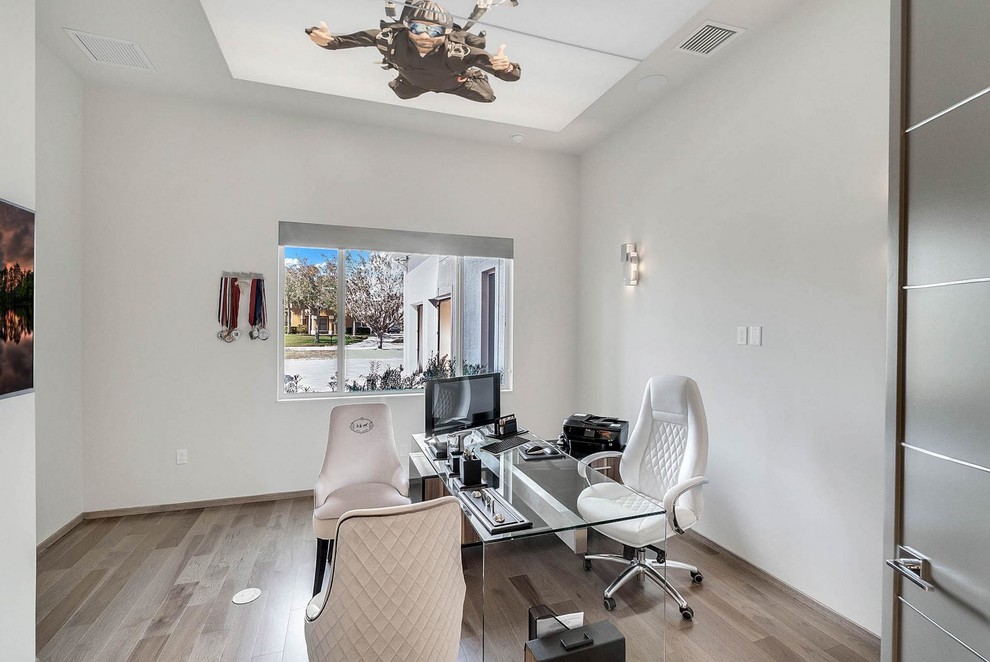 Cette image montre un bureau minimaliste de taille moyenne avec un mur blanc, un sol en bois brun, aucune cheminée, un bureau indépendant et un sol marron.