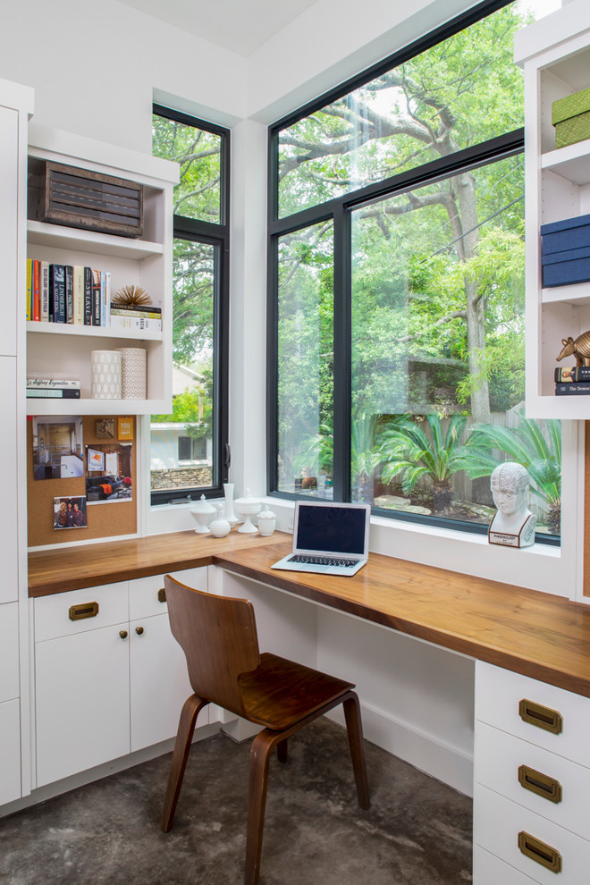 Classic home office in Austin with white walls, concrete flooring and a built-in desk.