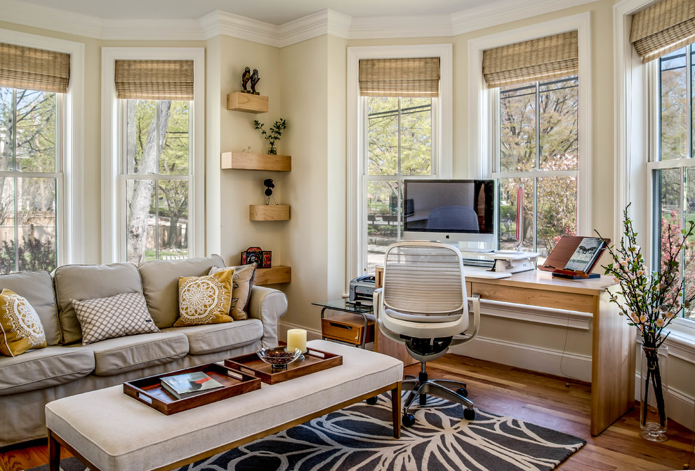 This is an example of a large traditional study in Boston with beige walls, medium hardwood flooring, a freestanding desk, no fireplace and brown floors.