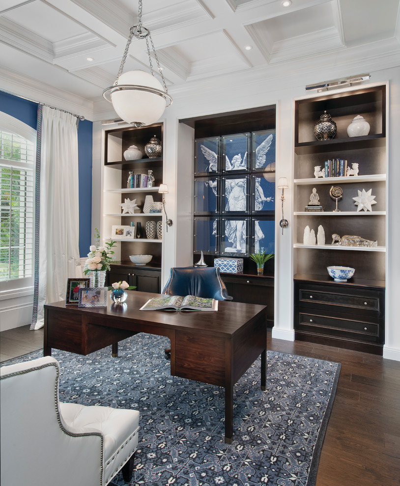Inspiration för hemmabibliotek, med blå väggar, mörkt trägolv och ett fristående skrivbord