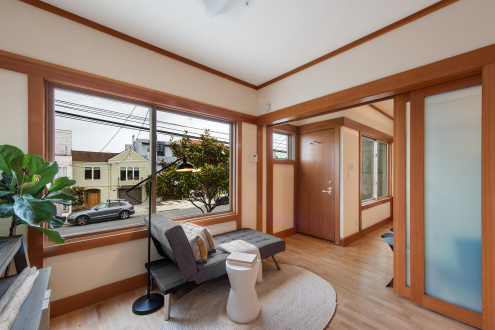 Diseño de despacho de estilo zen de tamaño medio con paredes blancas, suelo de madera clara, escritorio independiente, suelo marrón y panelado