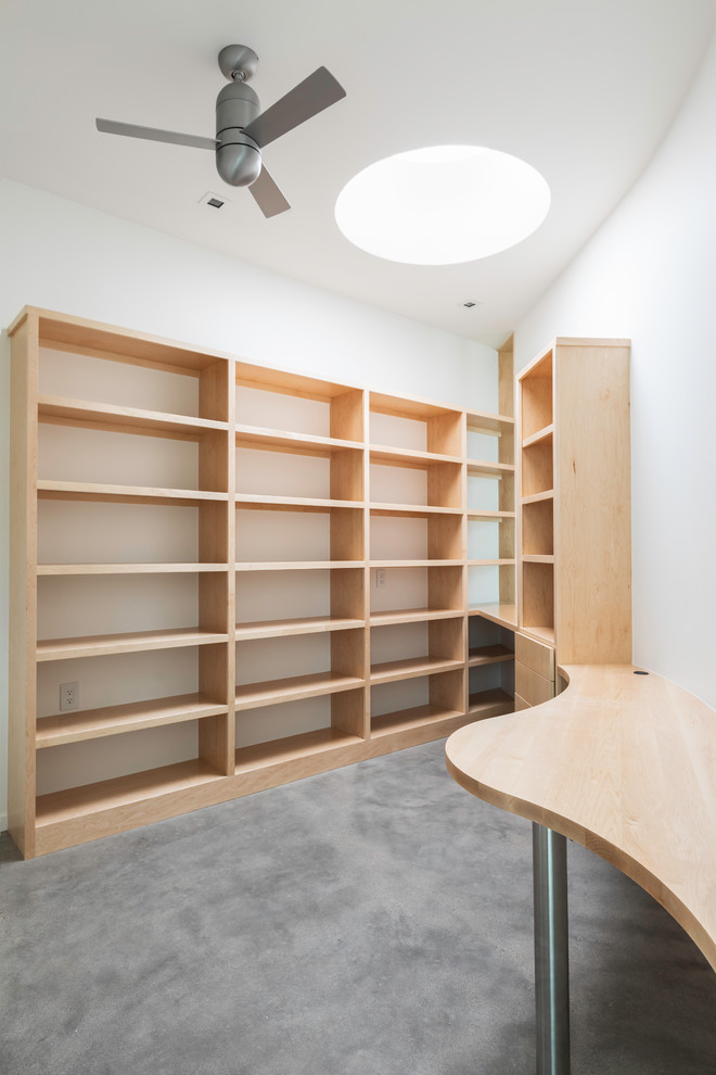 Ejemplo de despacho actual pequeño con biblioteca, paredes blancas, moqueta, escritorio empotrado y suelo gris