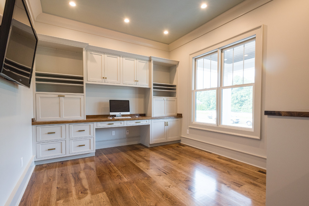 Example of a mid-sized farmhouse built-in desk medium tone wood floor and brown floor study room design in Atlanta with white walls