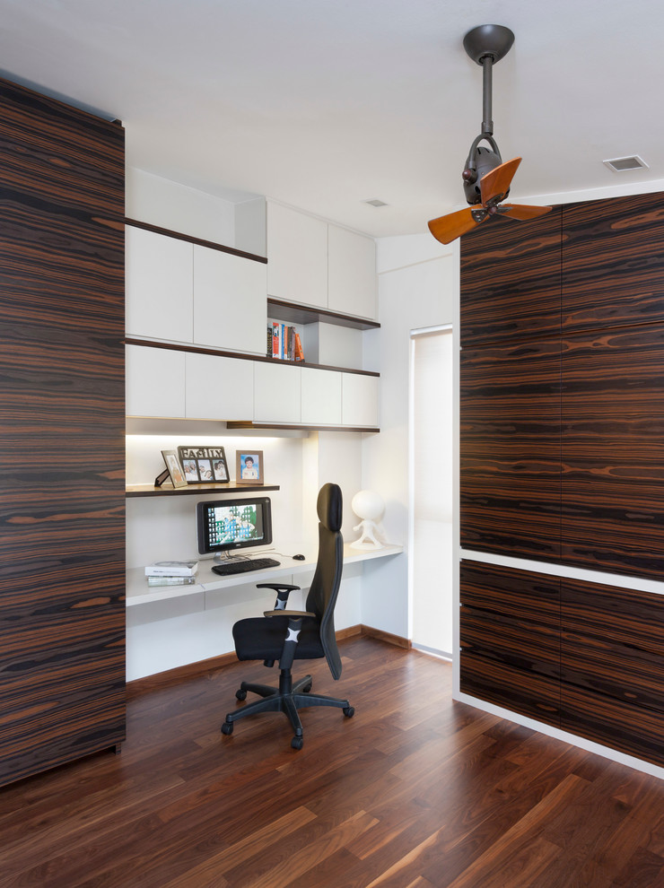 Foto på ett funkis arbetsrum, med vita väggar, mörkt trägolv och ett inbyggt skrivbord