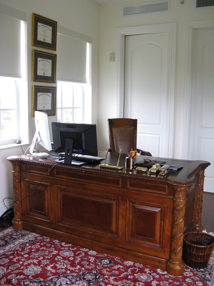 Idee per un piccolo studio tradizionale con parquet scuro, scrivania autoportante e pareti beige