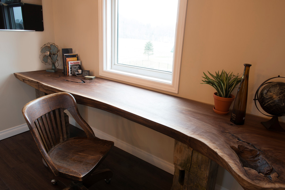 Imagen de estudio rústico grande con paredes beige, suelo de madera oscura y escritorio empotrado