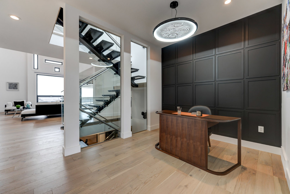 Imagen de despacho actual de tamaño medio sin chimenea con paredes blancas, suelo de madera clara, escritorio independiente y suelo beige