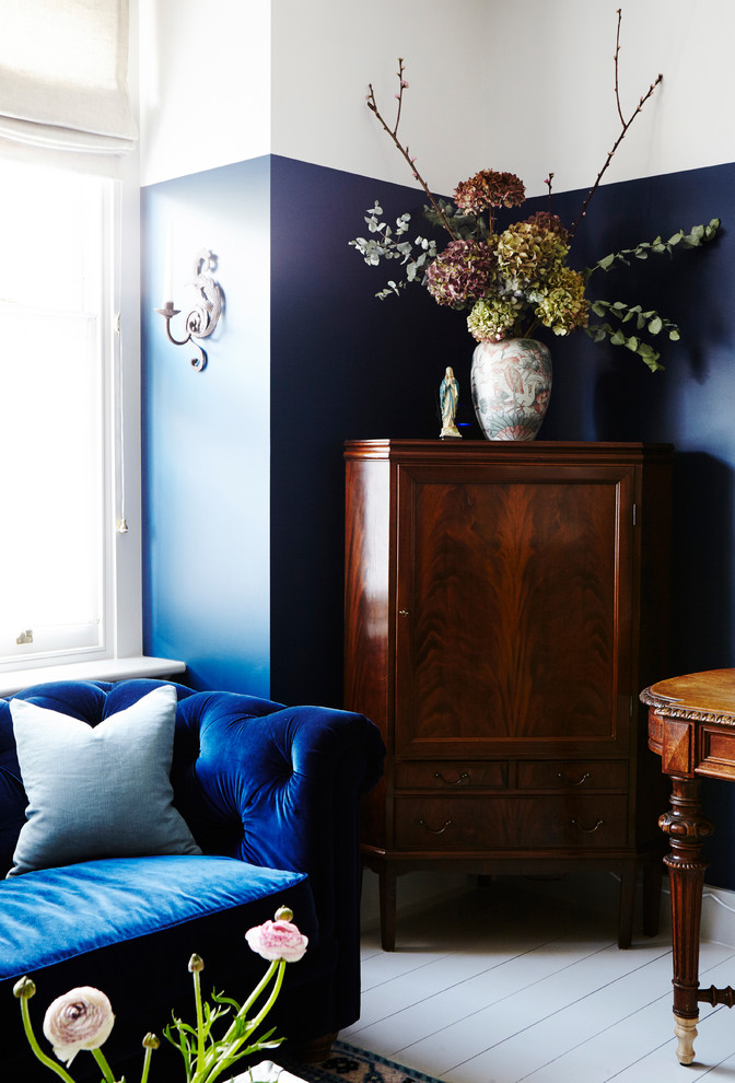 Großes Uriges Arbeitszimmer mit Arbeitsplatz, blauer Wandfarbe, gebeiztem Holzboden, Kaminofen, Kaminumrandung aus Backstein, freistehendem Schreibtisch und weißem Boden in London
