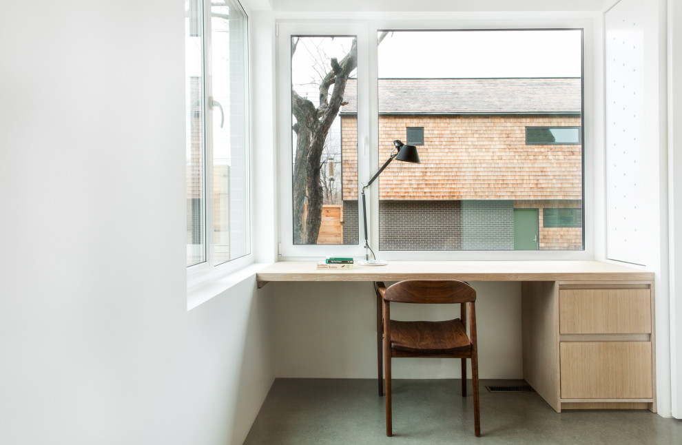 Ejemplo de despacho actual pequeño con paredes blancas, suelo de cemento, escritorio empotrado y suelo gris