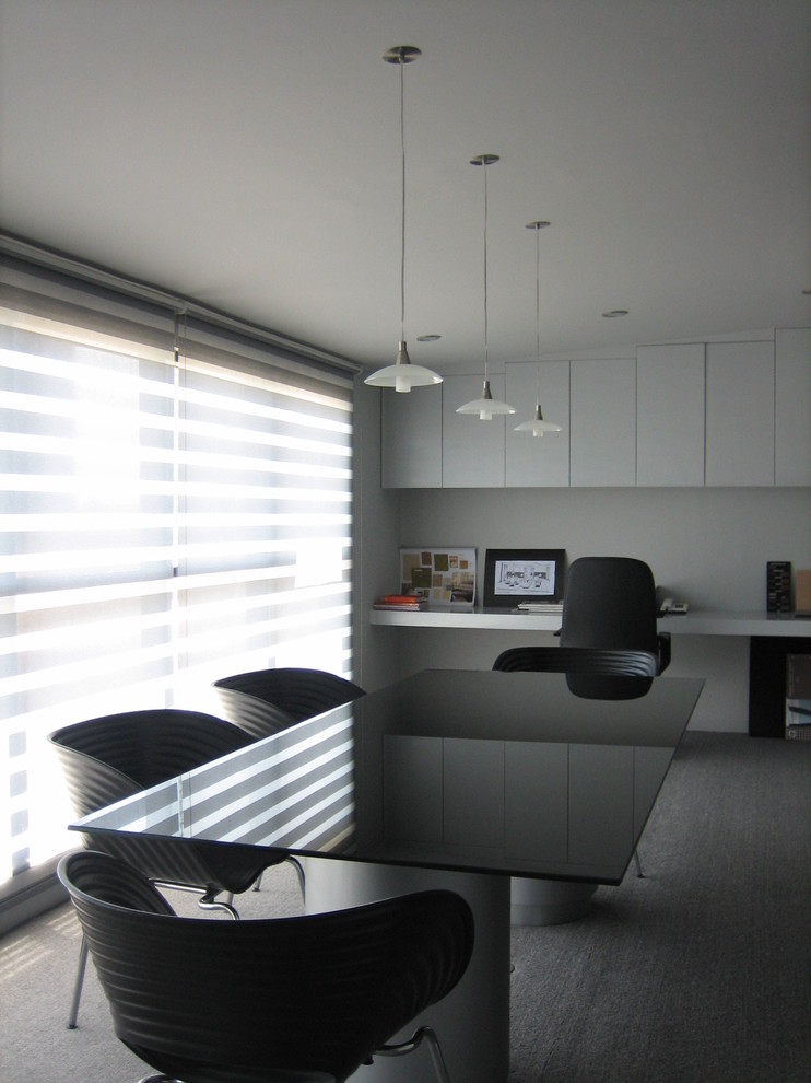 Réalisation d'un bureau design avec un mur blanc, moquette et un bureau intégré.
