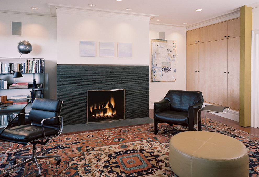 This is an example of a medium sized modern study in San Francisco with beige walls, dark hardwood flooring, a standard fireplace, a tiled fireplace surround and a freestanding desk.