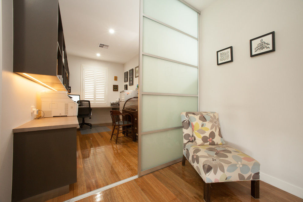 Imagen de despacho contemporáneo de tamaño medio con paredes blancas, suelo de madera en tonos medios y escritorio empotrado