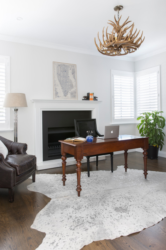 Exempel på ett klassiskt arbetsrum, med grå väggar, mörkt trägolv, en standard öppen spis, ett fristående skrivbord och brunt golv