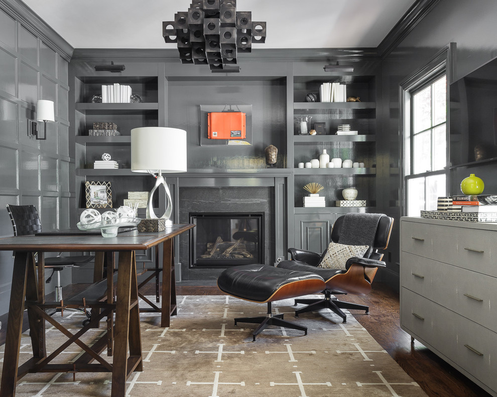 Ejemplo de despacho tradicional con paredes grises, suelo de madera oscura, todas las chimeneas y escritorio independiente