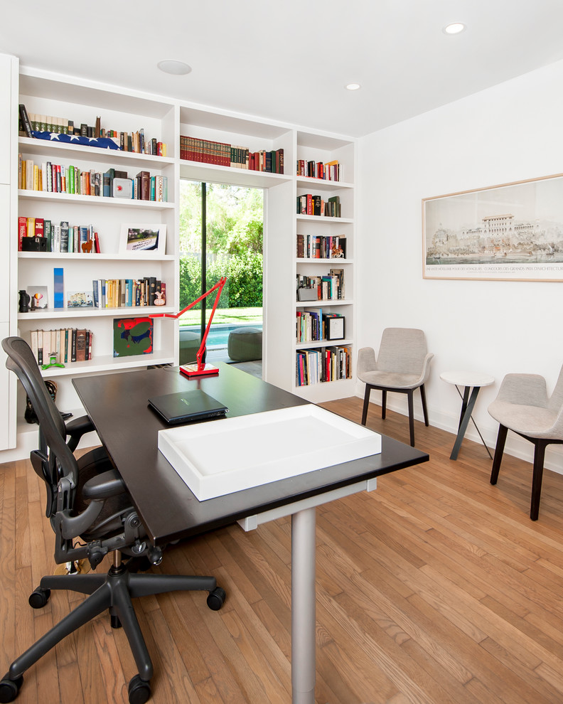 Aménagement d'un bureau contemporain avec un mur blanc, un sol en bois brun et un bureau indépendant.
