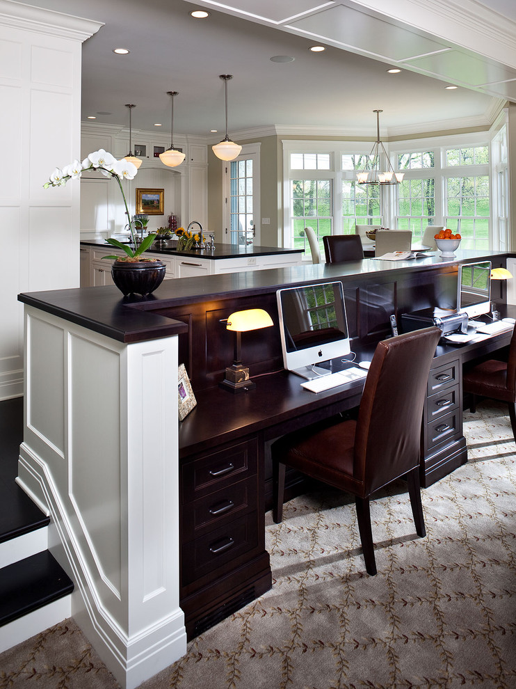 Aménagement d'un petit bureau classique avec un mur beige, moquette, un bureau intégré et un sol multicolore.