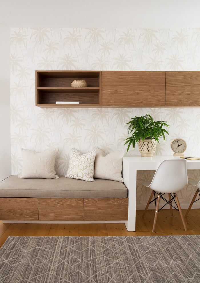 Cette image montre un bureau design de taille moyenne avec un mur beige, un sol en bois brun, un bureau intégré et un sol marron.