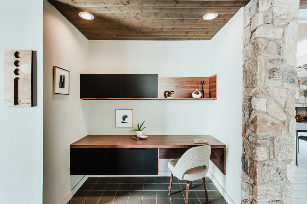 This is an example of a small study in Other with ceramic flooring, a built-in desk, grey floors and white walls.