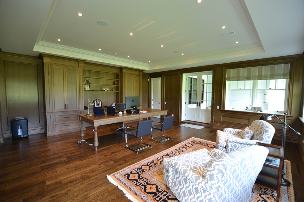 Modelo de despacho tradicional con paredes marrones, suelo de madera en tonos medios, escritorio independiente y suelo marrón