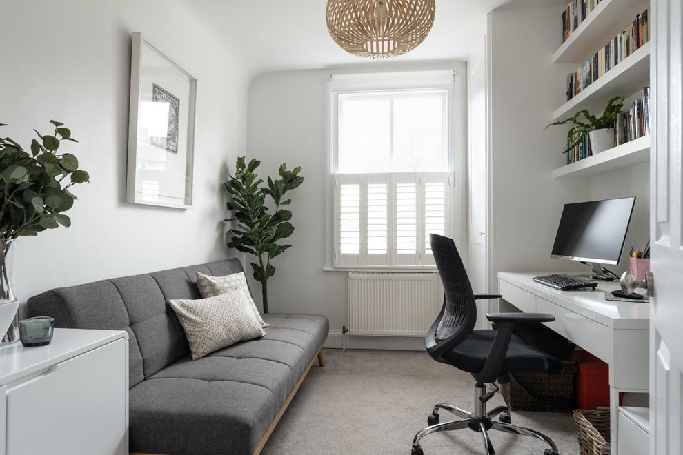 Modelo de despacho de estilo de casa de campo con paredes blancas, moqueta, escritorio independiente y suelo gris