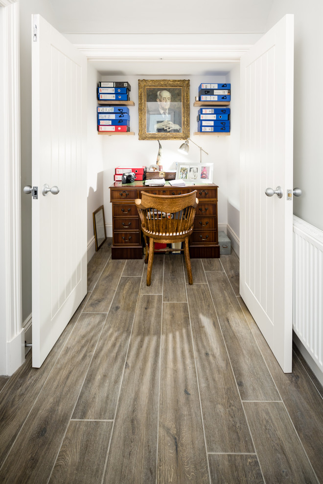 Ejemplo de despacho tradicional renovado pequeño con paredes blancas, escritorio independiente y suelo marrón