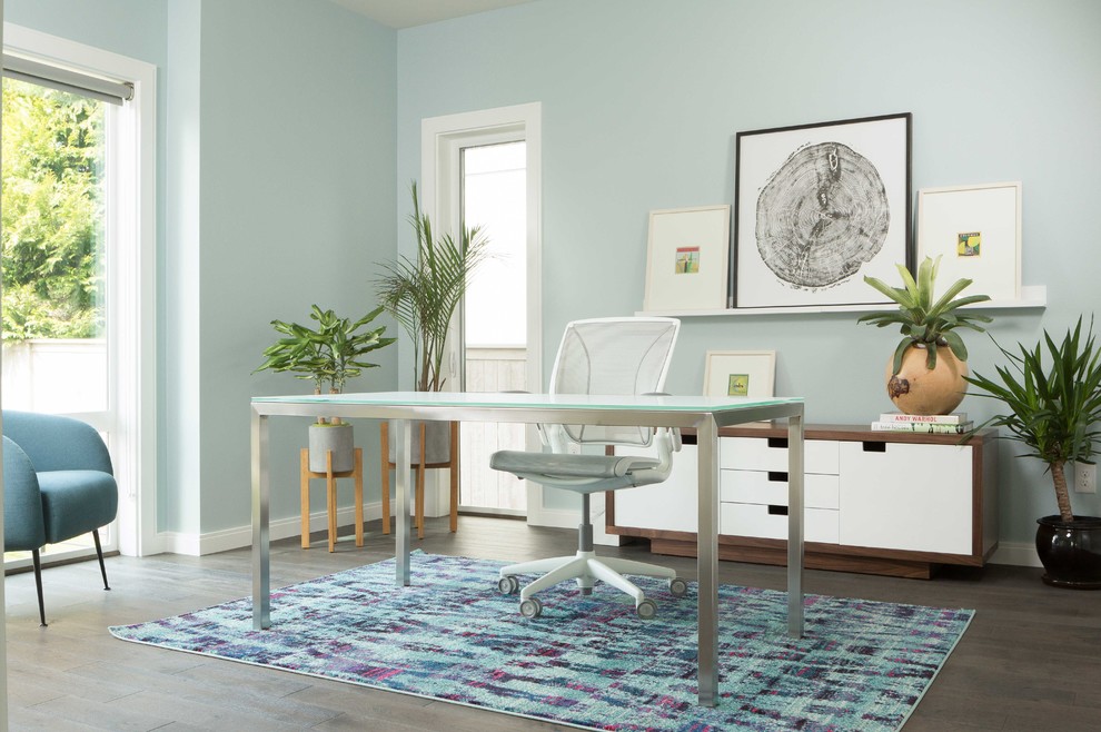 Diseño de despacho contemporáneo con paredes azules, suelo de madera en tonos medios y escritorio independiente