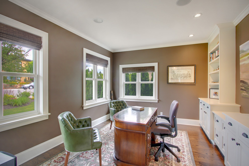 Klassisches Arbeitszimmer mit brauner Wandfarbe, braunem Holzboden und freistehendem Schreibtisch in Seattle