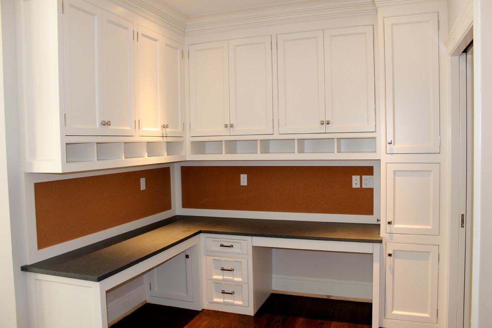 Kleines Klassisches Arbeitszimmer ohne Kamin mit braunem Holzboden, Einbau-Schreibtisch und weißer Wandfarbe in New York