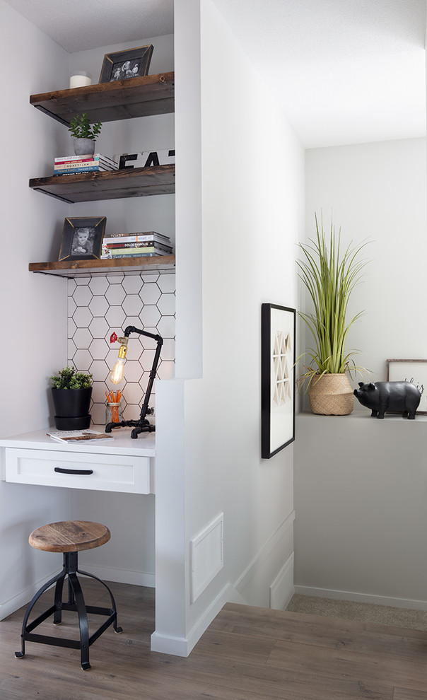 Ejemplo de despacho campestre pequeño sin chimenea con paredes blancas, suelo laminado y escritorio empotrado
