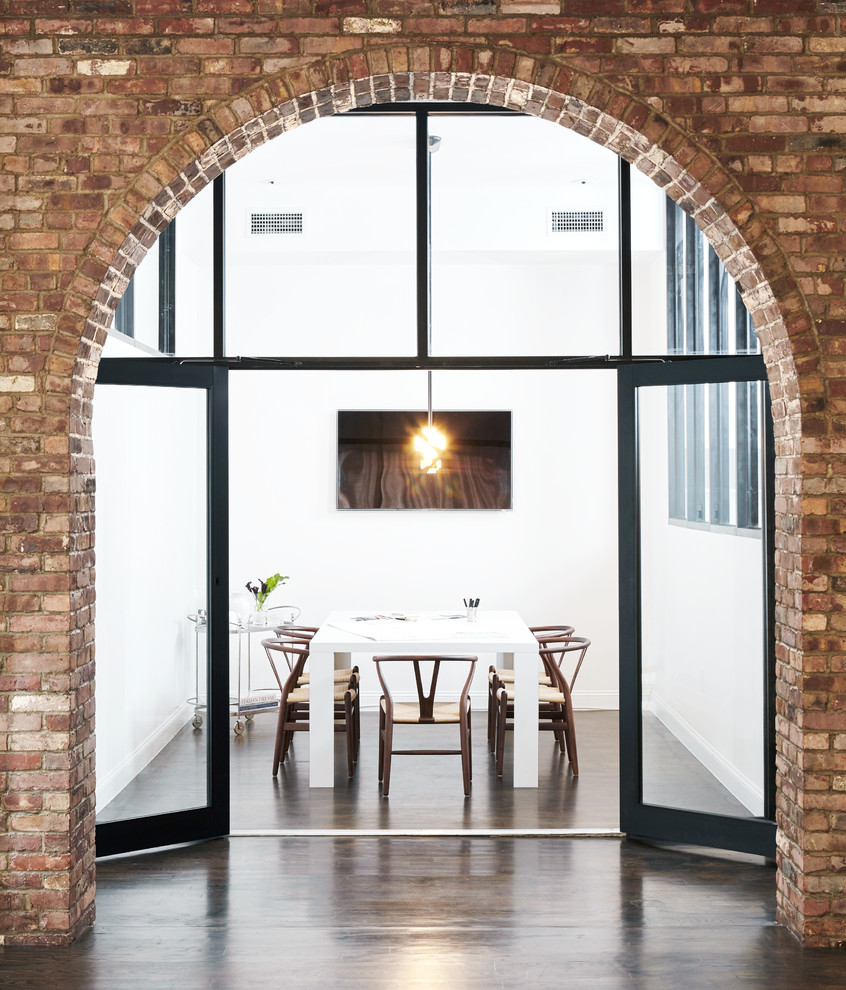 Cette photo montre une salle à manger moderne avec un mur blanc, parquet foncé, un sol marron et un mur en parement de brique.