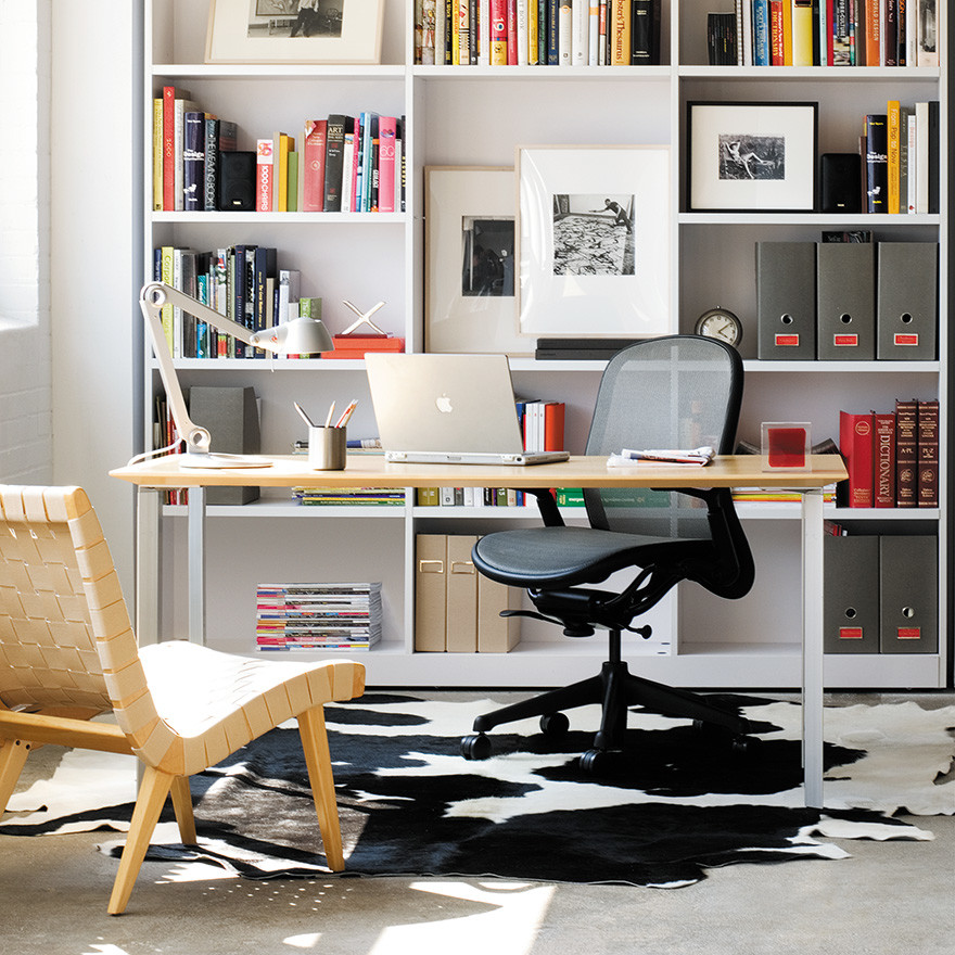 Пример оригинального дизайна: рабочее место в современном стиле с белыми стенами, бетонным полом, отдельно стоящим рабочим столом и серым полом