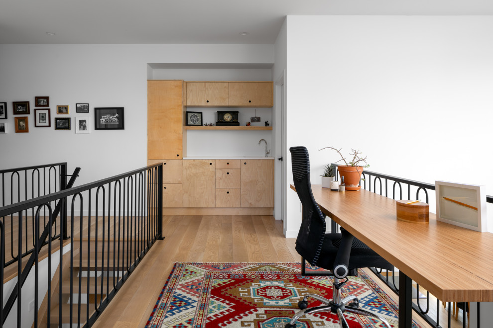 Inredning av ett modernt mellanstort arbetsrum, med vita väggar, mellanmörkt trägolv, ett fristående skrivbord och brunt golv