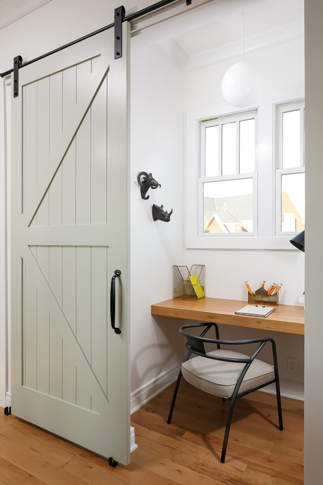 Inspiration for a small farmhouse built-in desk medium tone wood floor study room remodel in Louisville with white walls