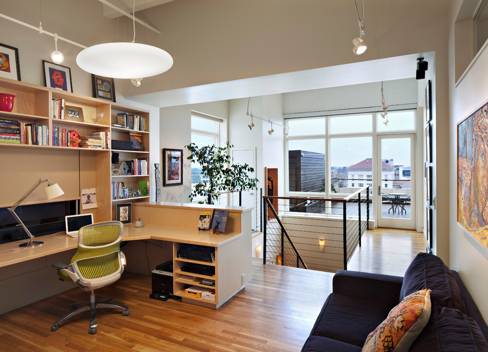 Ejemplo de despacho actual con paredes blancas, suelo de madera en tonos medios y escritorio empotrado