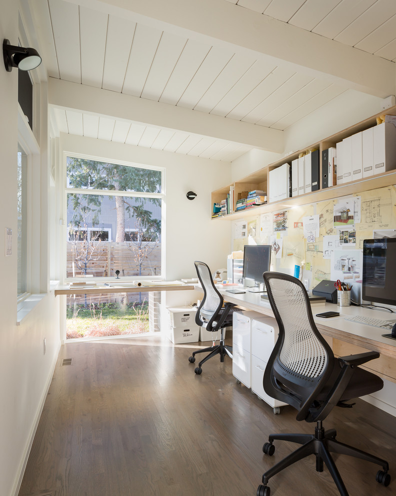 Foto på ett 50 tals hemmastudio, med mellanmörkt trägolv och ett inbyggt skrivbord