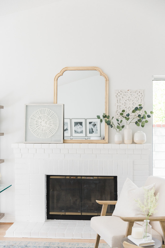 Inredning av ett klassiskt litet arbetsrum, med vita väggar, ljust trägolv, en standard öppen spis, en spiselkrans i tegelsten, ett fristående skrivbord och brunt golv