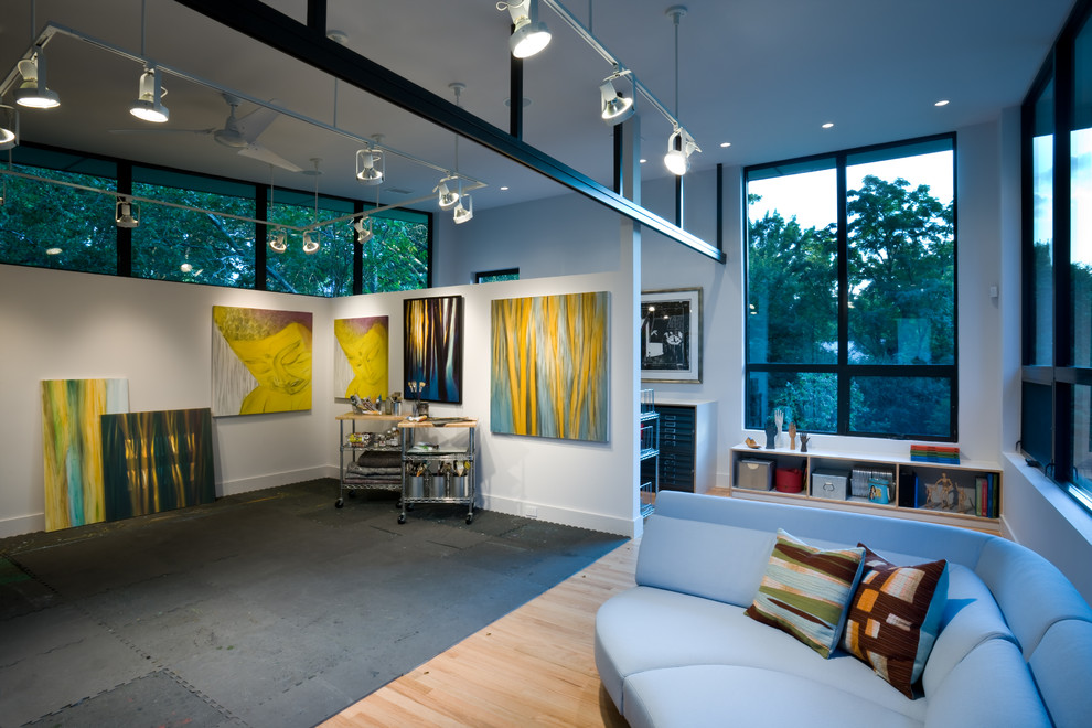 Cette photo montre un bureau tendance de type studio avec un mur blanc et un sol en bois brun.