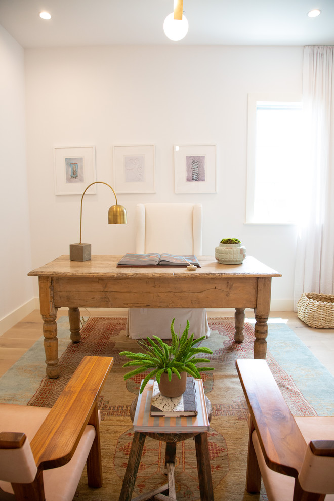 Ejemplo de despacho costero grande con paredes blancas, suelo de madera clara, escritorio independiente y suelo marrón