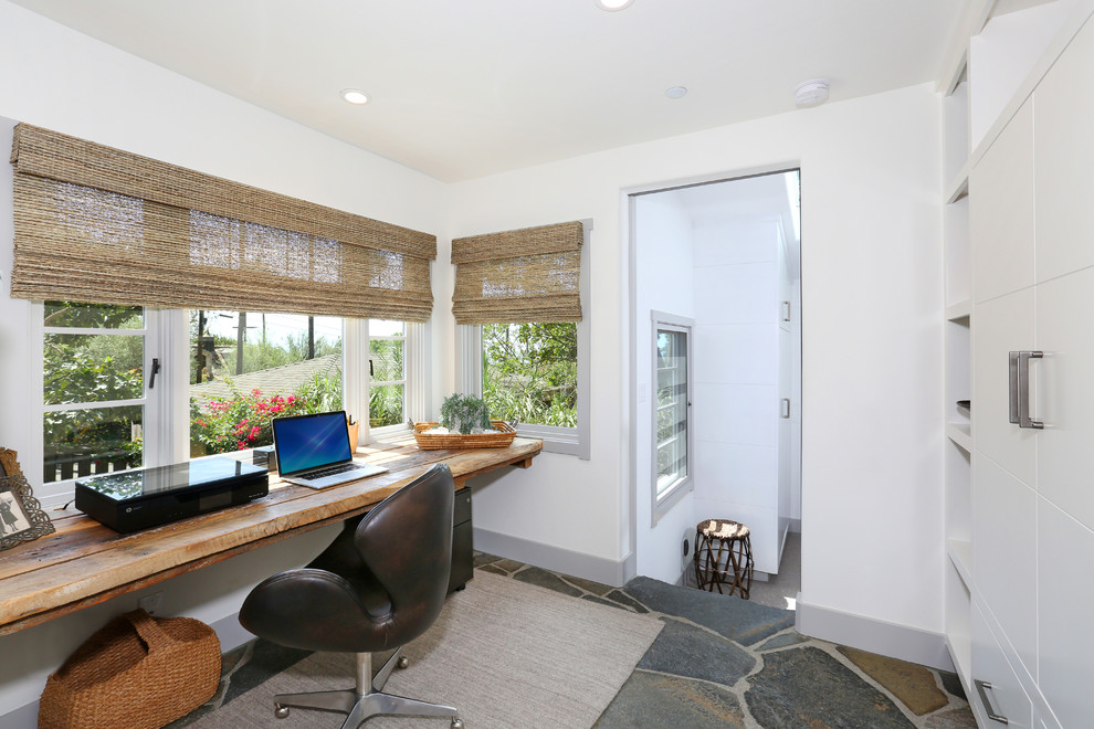 Diseño de despacho costero con paredes blancas, suelo de pizarra y escritorio empotrado