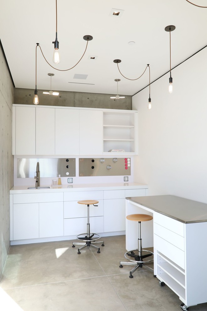 Cette photo montre un bureau tendance de taille moyenne et de type studio avec un mur blanc, sol en béton ciré, aucune cheminée, un bureau intégré et un sol gris.